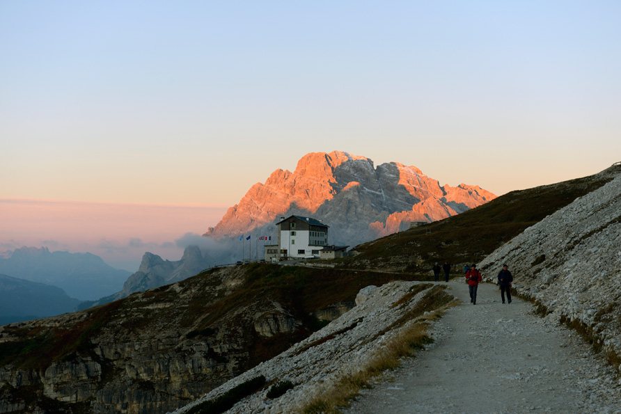 Berghütte im Abendrot mit Wanderern in den Dolomiten